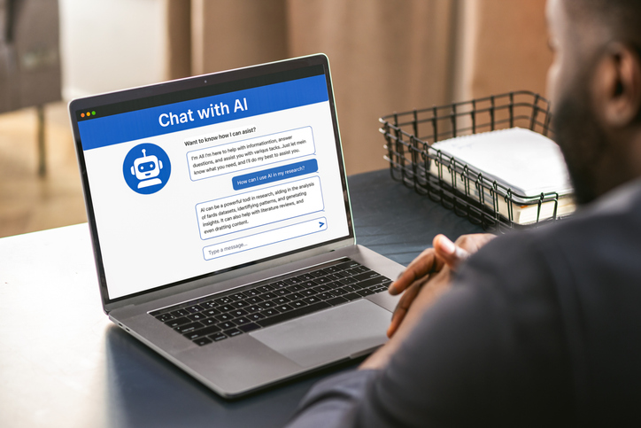 Man looking at a laptop screen with an AI chatbot conversation open.
